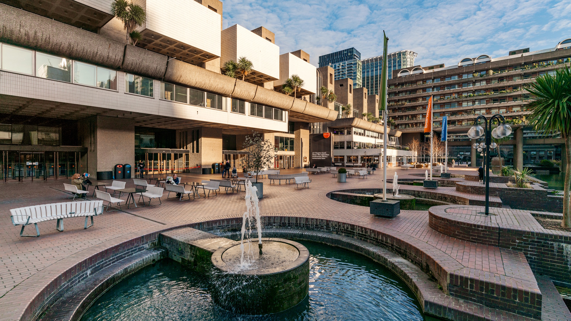 The courtyard of the Barbican. Image courtesy of London & Partners/Jon Reid. Courtyard fountains and benches at Barbican Centre on a clear sunny day.