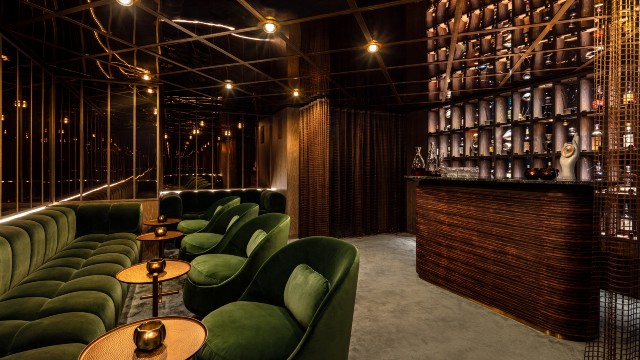 End your days in style with a nightcap in The Green Room. Credit: The Londoner. Image courtesy of The Londoner. A dimly lit bar area with plush seating, mirrored ceiling and a wall of drinks bottles behind the bar