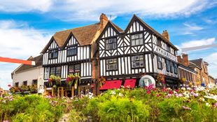 Flowers outside Tudor buildings with a blue sky overhead in Stratford-upon-Avon