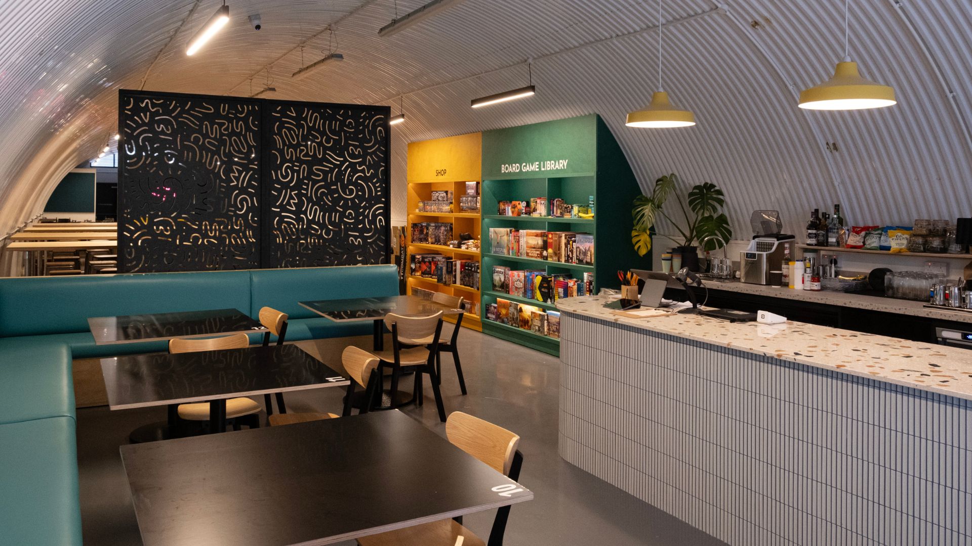 Choose your battlefield to compete with friends at Bad Moon Cafe. Image courtesy of Bad Moon Cafe. Interior of Bad Moon Cafe with tables at the front and board games stacked at the back.