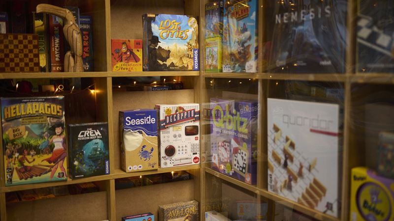 Board game shelf with several board games lined up.