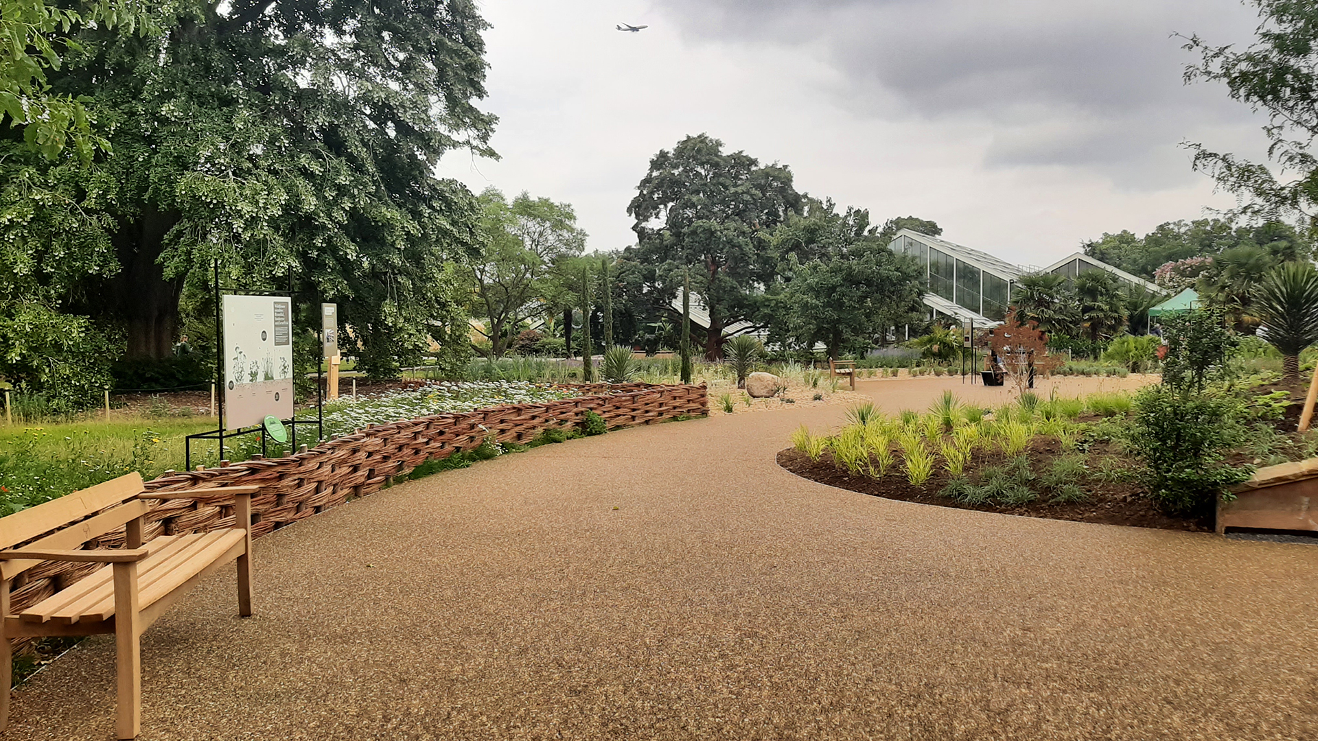 Explore the meadows at the Carbon Garden at Kew Gardens. © Visit London/Sigrun Tomicki The image shows a curved pavement that is surrounded by plants and flowers with the Princess of Wales conservatory in the background.