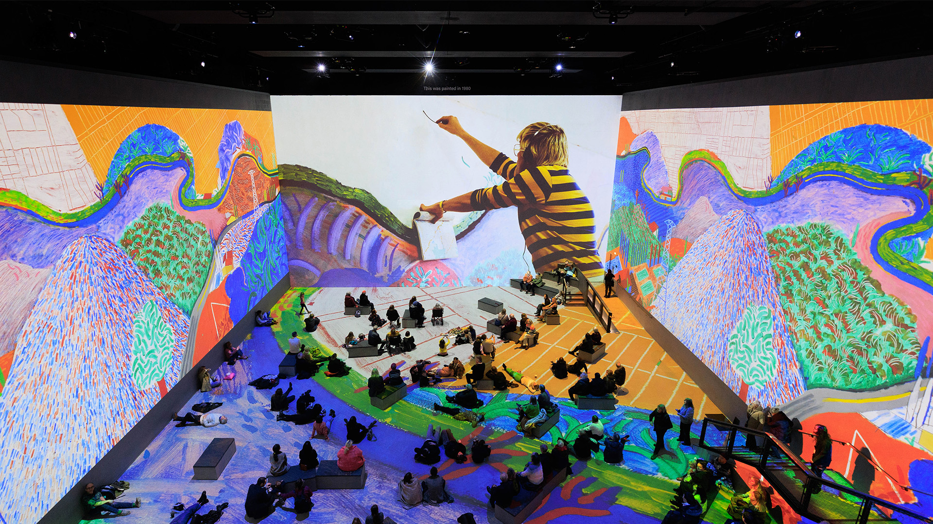 Hockney paints a piece inspired by the roads of Los Angeles. Image courtesy of Lightroom. Wraparound screens at Lightroom project bright, bold Hockney paintings inspired by Los Angeles.