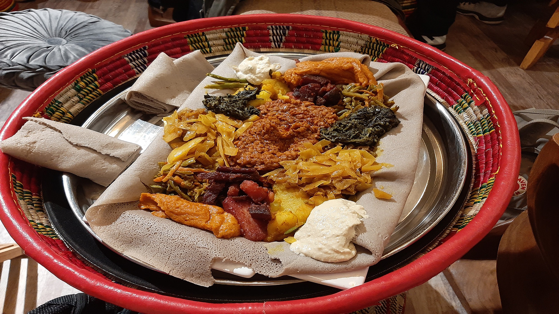 Scoop up various toppings as part of the injera platter at Beza © Visit London/Sigrun Tomicki. A large plate with a flat injera bread which has various colourful toppings and sauces on top.