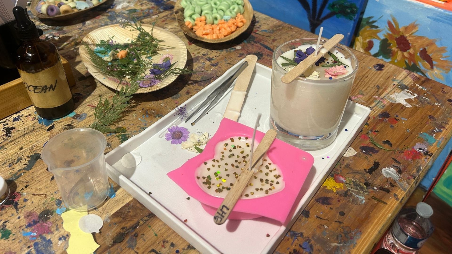 Have a go at candle making with Art Play. Image courtesy of Charlotte Pritchard. A table with a tray of materials to make candles on top, including wooden sticks, a candle holder and decorations.