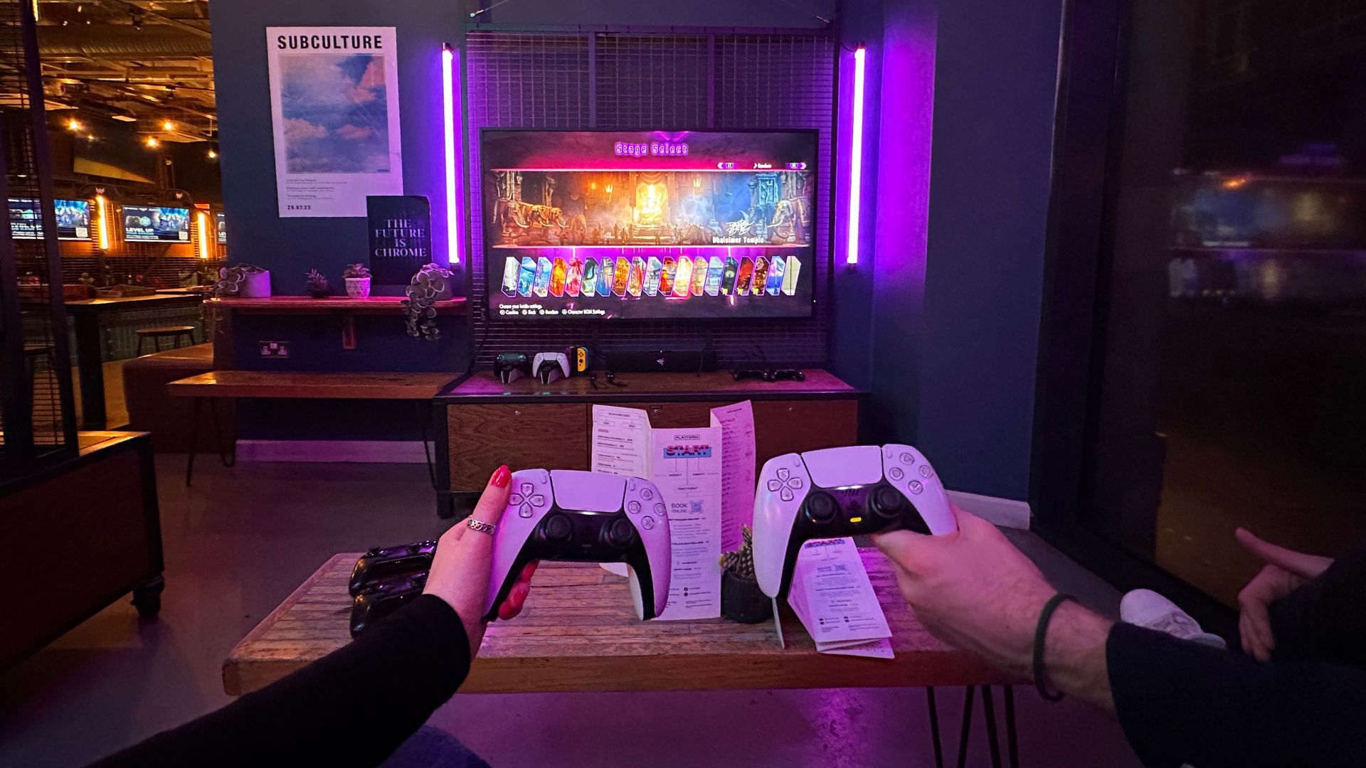 Get competitive at Platform gaming bar in Shoreditch © Visit London/Kirstine Spicer. Two people hold games controllers infront of a screen showing a retro game at Platform in Shoreditch.