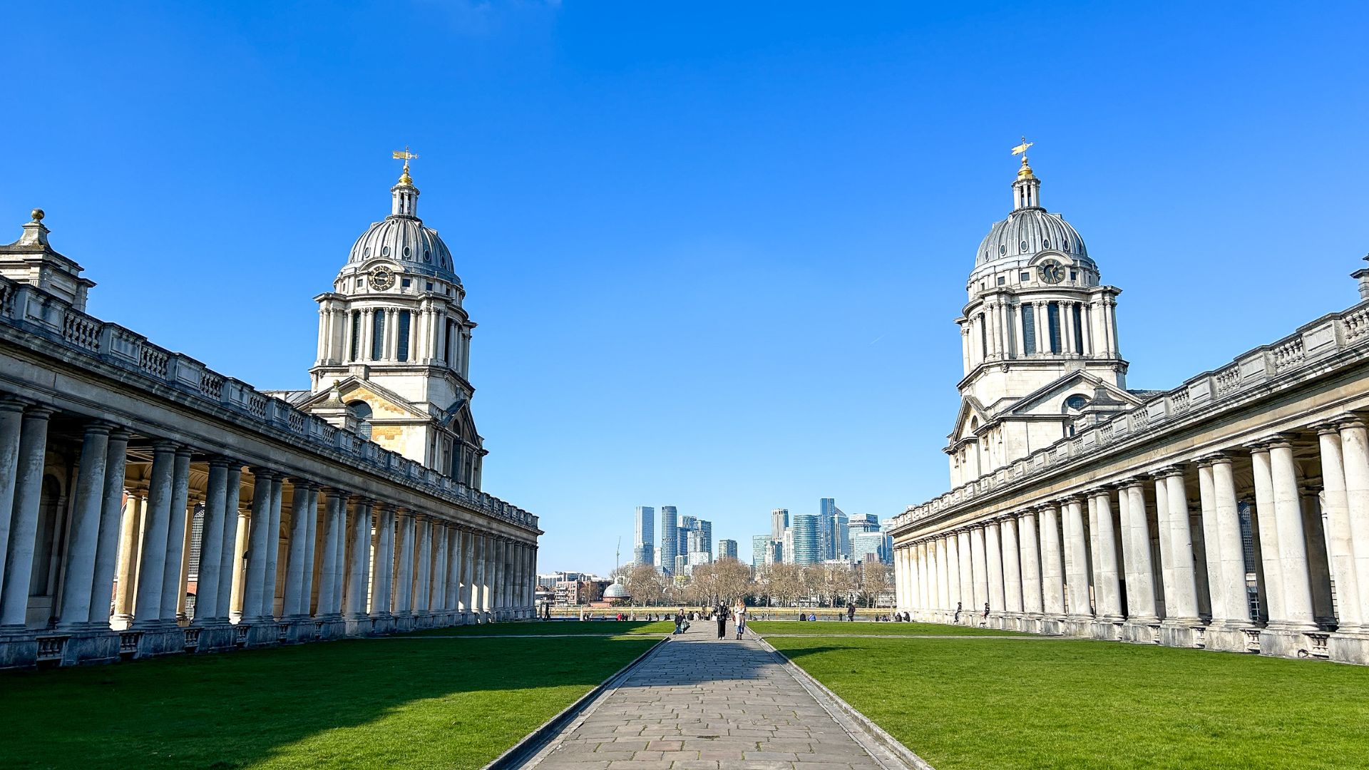 Old Royal Naval College in Greenwich. © Visit London/Hannah Cornish a picture taken from the middle of Old Royal Naval College, with blue skies and a glimpse of the London skyline in the background
