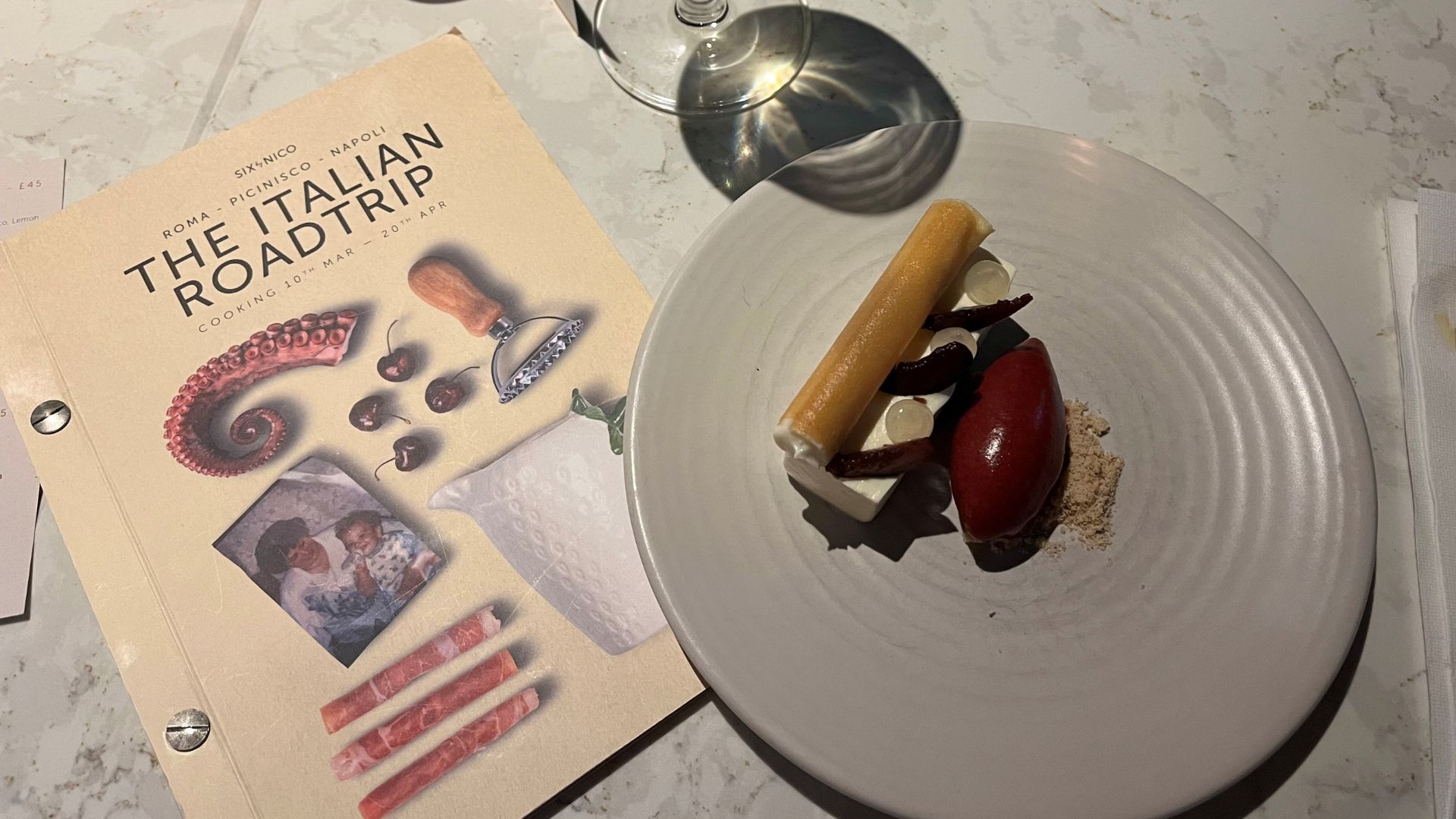 Delight in a themed tasting menu at Six by Nico. Photo credit: Charlotte Pritchard A table with an italian menu and a savoury dish at the six by nico italian tasting meal.