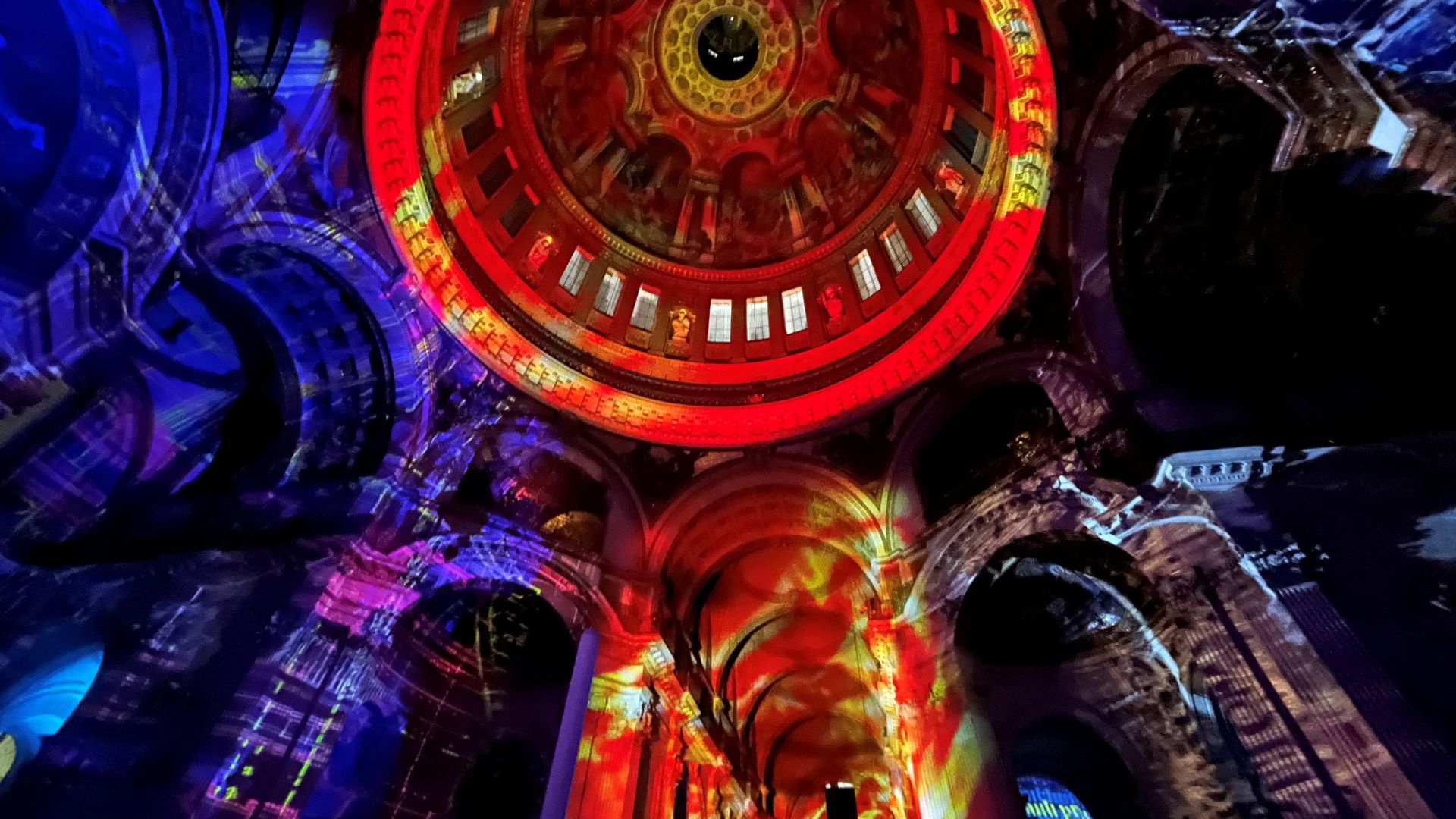 The interior of St Paul's Cathedral bathed in light as part of the ‘Luminous’ installation by Luxmuralis © Visit London/Charlotte Pritchard. Red, yellow, purple and blue graphics illuminte the interiors of the galleries at St Paul's Cathedral as part of the 'Luminous’ installation by Luxmuralis.