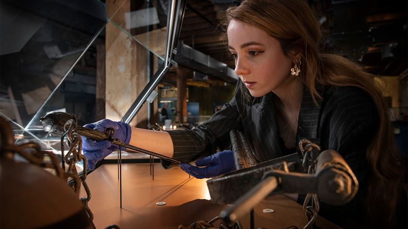 A conservation staff member at the London Museum Docklands carefully places a 16th-century dagger into a glass display case, part of the Secrets of the Thames exhibition.