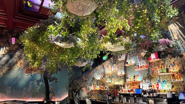 The Glade at Sketch London features low-hanging branches and umbrellas in a room painted in woodland tones.