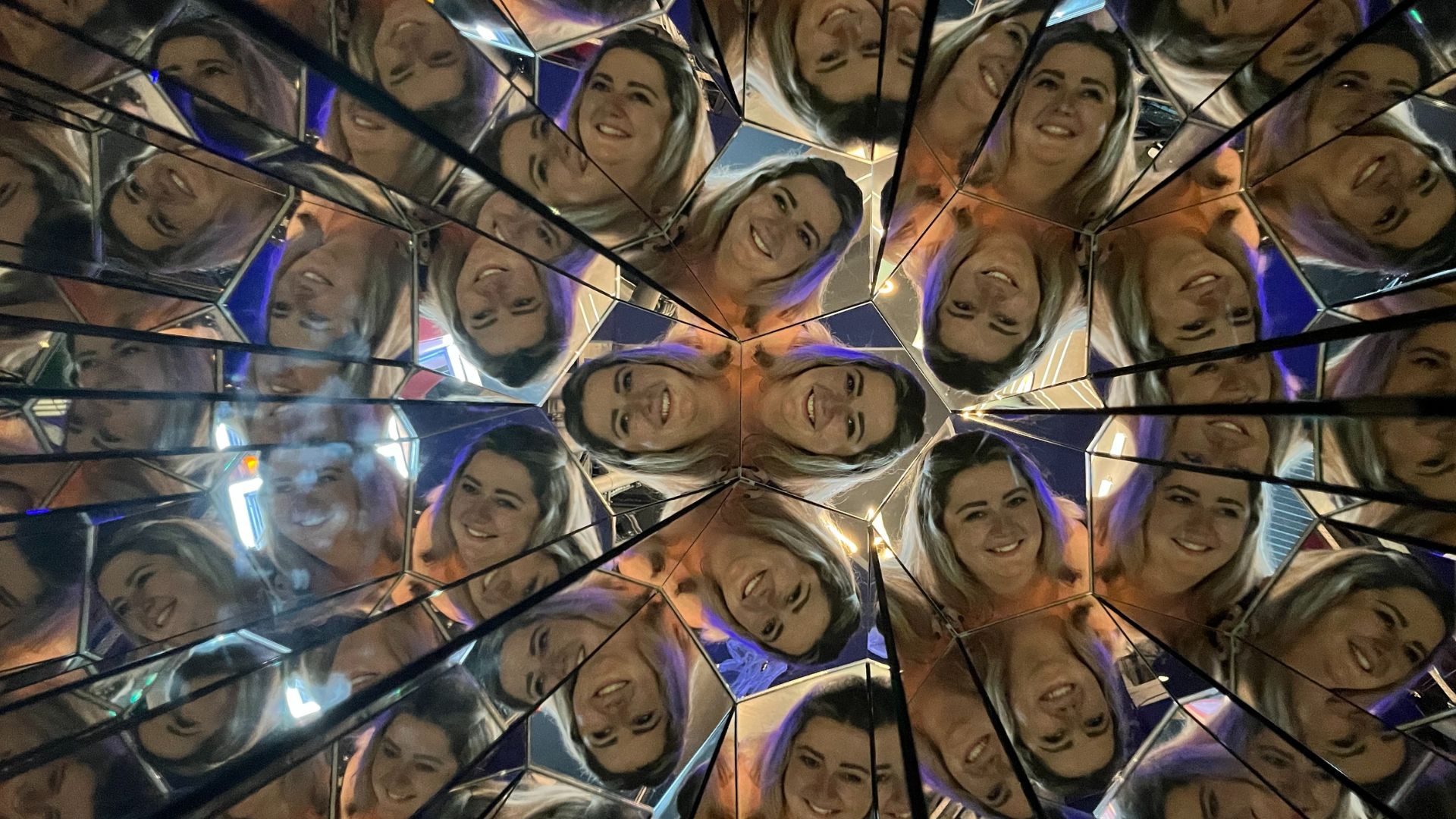 Step into the kaleidoscope of colour and snap funny, distorted photos. © Visit London/Hannah Cornish a woman having her photo taken in a kaleidoscope, with her face showing multiple different times