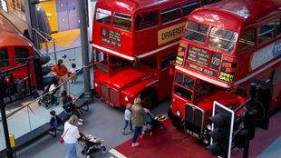 Families make their way through two red double-decked buses at the London Transport Museum.