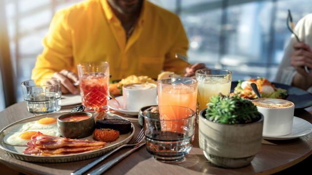 Breakfast at Darwin Brasserie, Sky Garden. Image © visitlondon/City of London/Antoine Buchet People sat around a table enjoying a cooked breakfast and coffee, with the London skyline in the background