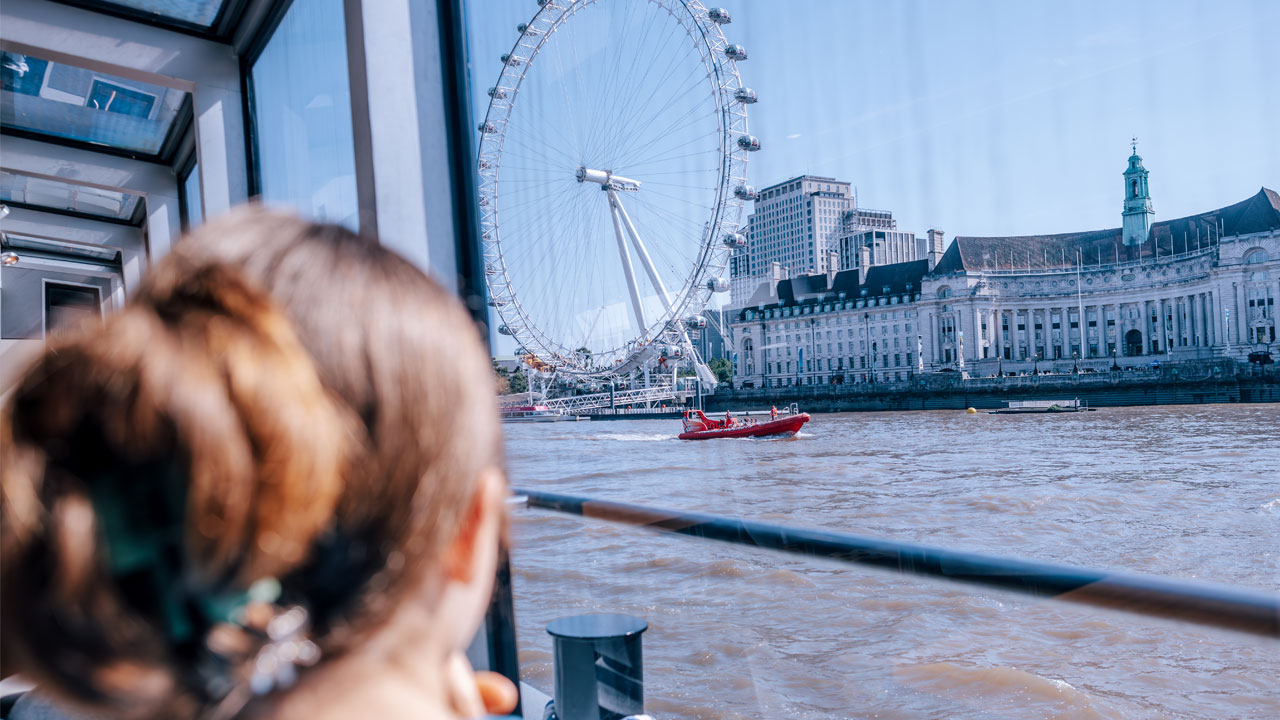 Person looking towards the London Eye from a Thames river cruise