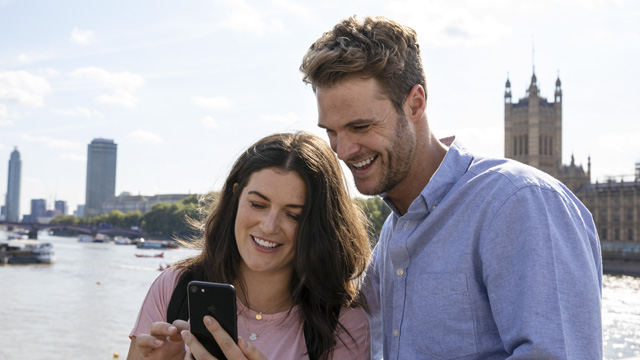 Man and woman using The London Pass mobile pass by the Thames