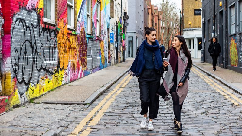 Check out these spots in London that have served as the backdrop to some of the most iconic romantic films. Credit: Jon Reid/visitlondon.com. Image courtesy of visitlondon.com. Couple smile at each other as they walk down road past Shoreditch street art on a date.