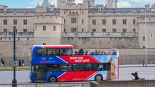 Hop-on hop-off bus driving past Tower of London.