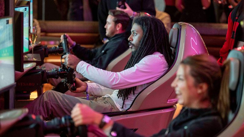 Experience the excitement and thrills of a F1 racing simulator activity bar at F1® Arcade. Image courtesy of F1® Arcade. Three friends sat in gaming chairs in front of screens at F1 Arcade racing