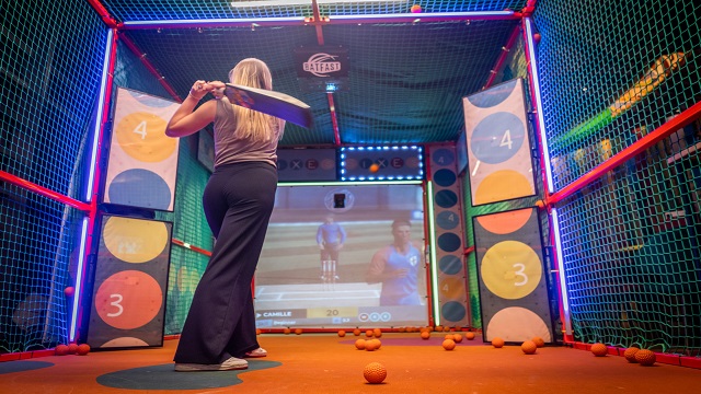 Fun cricket activity bar in London. Image courtesy of Sixes Social Cricket. low angle shot of a person swinging a cricket bat with targets in a framework to hit