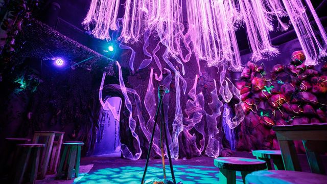 low angle shot of an immersive mystical dark room, with vibrant pink, purple and blue lights and hanging lights