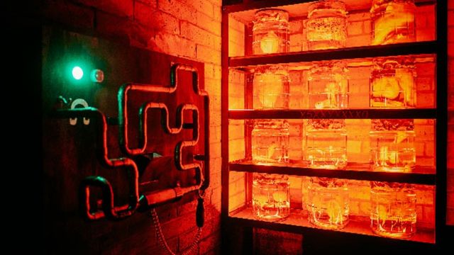 Become super hero spies for the day at Aim Escape. Image courtesy of Red Letter Days. An orange escape room with a shelf of jars filled with mysterious ingredients and pipes on the adjacent wall.
