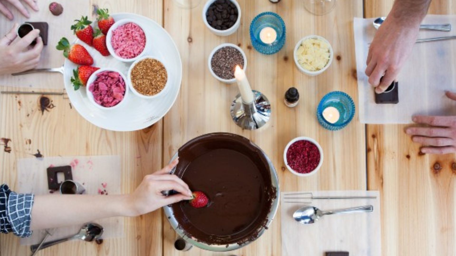 Chocolate-making class in London. Image courtesy of Red Letter Days. Chocolate fondue, strawberries, nuts, seeds, almonds and candles laid out on a wooden table.