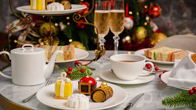 festive afternoon tea presented on small plates with finger sandwiches and present and bauble themed sweet treats