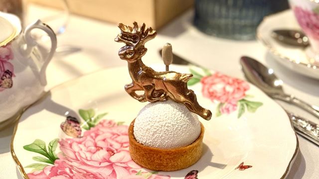 christmas themed patisserie with a chocolate golden reindeer on top, presented on a small white and pink flowery plate