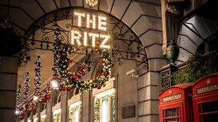The lights of the ritz hotel in london with holly wreaths and a red phone box. 
