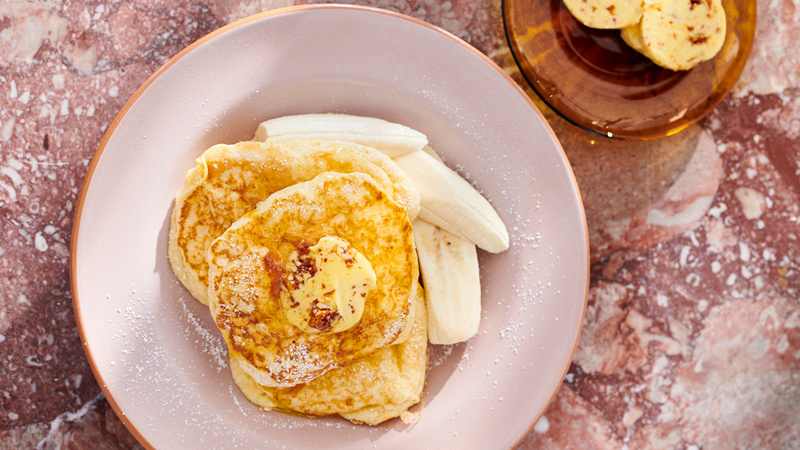 Delight in ricotta hotcakes with fresh banana and honeycomb butter at Granger & Co. Credit: Mikkel Vang. Image courtesy of Granger & Co. A plate of ricotta hotcakes with fresh banana and honeycomb butter
