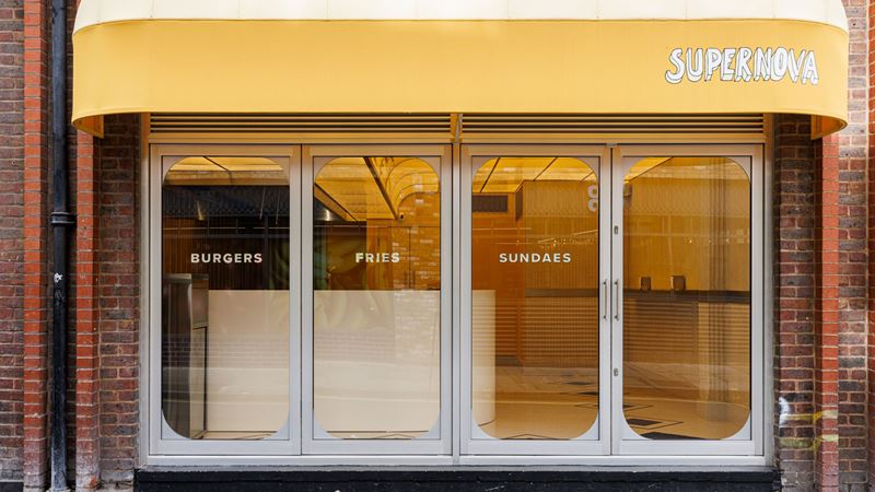 It's worth queuing for the smashed patty and hand-cut fries at Supernova. Credit: Supernova. Image courtesy of Supernova. A photo of the exterior of Supernova in Soho with the logo printed on a yellow background with "burgers, fries, sundaes" printed on the glass windows