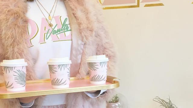 A person holds a tray of pink and palm tree coffee cups at palm vaults cafe in london.