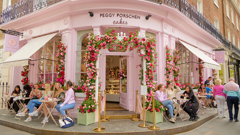 Head to Peggy Porschen and snap photos of the cakes that are just as Insta-worthy as the building they are made. Credit: Peggy Porschen. Image courtesy of Peggy Porschen. A photo of the baby pink exterior of Peggy Porschen with people sat around tables outside and flowers lining the entrance with the logo above the door