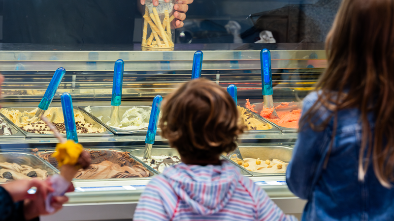 Savour fresh natural Italian ice cream at Oddono's. Credit: Simon Camper. Image courtesy of Oddono's. Two children look on at the trays of ice cream from behind the glass counter
