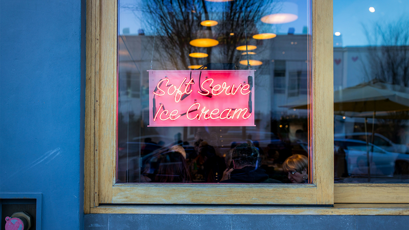 Enjoy delicious soft serve ice cream in London. Credit: Jason Leung. Image courtesy of Unsplash. A pink neon sign outside an ice cream shop with the words "soft serve ice cream"