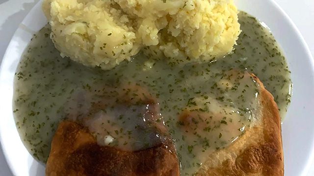 Two pies, some mash potato and green "liquor" sauce, on a white plate.