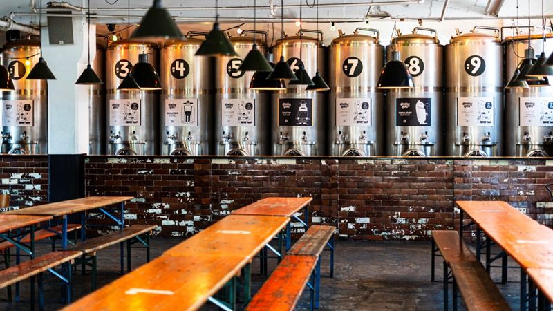 Try the vast range of freshly brewed beers at Howling Hops Brewery and Tank Bar in Hackney. Credit: Howling Hops. Image courtesy of Howling Hops. A photo of the brewing tanks lining the industrial Howling Hops brewery in Hackney with low hung lamps and bench seating