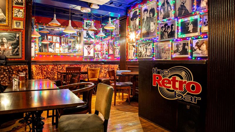 Sing your heart out to iconic tunes at Retro Bar, a west London hidden gem. Credit: Rachel Hardwick. Image courtesy of Retro Bar. A photo of the interior of Retro Bar with photos of rock and pop musicians covering the walls, colourful lights and comfy chairs and tables