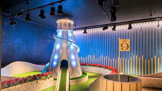 A helter skelter golf obstacle at Swingers West End © Competitive Socialising. Image courtesy of Competitive Socialising. A flag at hole nine next to an illuminated helter skelter golf obstacle at Swingers West End.