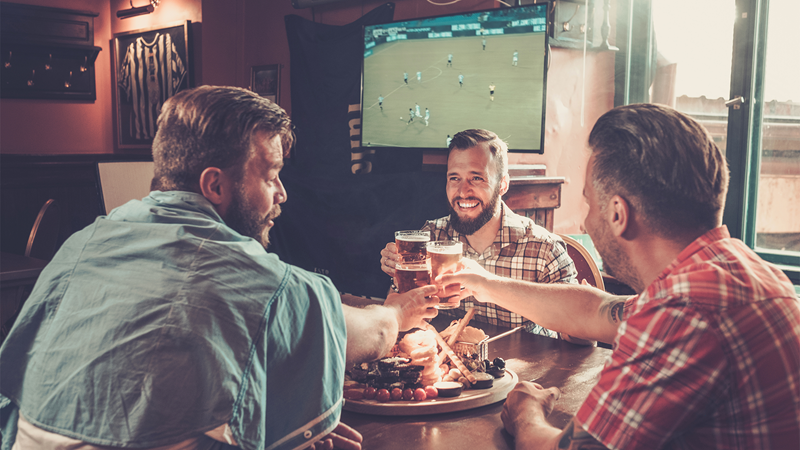 Watch live sports and enjoy classic pub dishes at an Irish pub in London. Credit: Shutterstock. Image courtesy of Shutterstock. A group of friends enjoying the football and a pub lunch