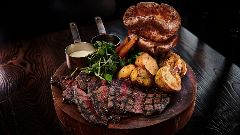 Start your Sunday off right with a roast at The Jugged Hare. Credit: Tom Webb. Image courtesy of The Jugged Hare. A wooden board with cuts of roast beef, potatoes, carrots, Yorkshire puddings and two sauces
