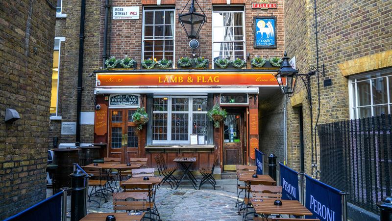 Tucked away in Covent Garden's backstreets, the Lamb & Flag holds a rich charm and heritage. Credit: Shutterstock. Image courtesy of Shutterstock. A photo of the exterior of the Lamb and Flag pub with wooden chairs and tables out the front