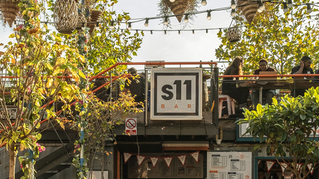 People sat on benches on a roof terrace having a drink in the sun