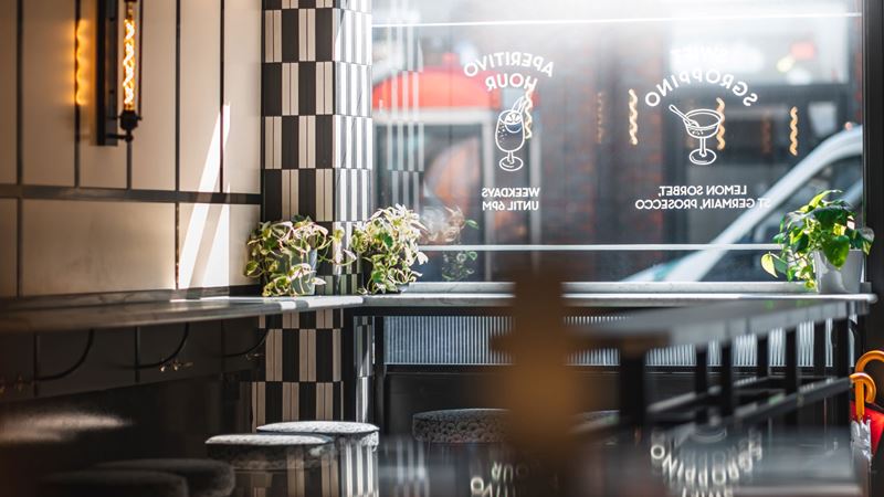 A photo of the interior of Swift Borough, a laidback cocktail bar with tiled walls, warm lighting and bar stools