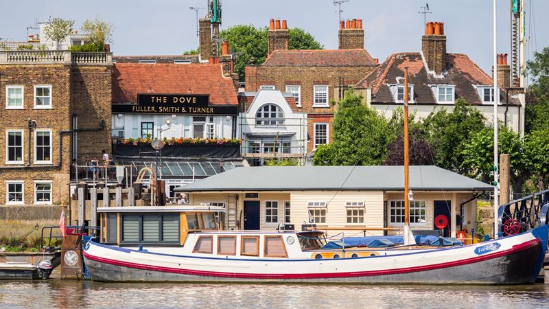 The Dove in Hammersmith boasts a garden and terrace with sweeping views of the water. Credit: Shutterstock. Image courtesy of Shutterstock. A photo of the exterior of The Dove in Hammersmith with a boat on the Thames in the foreground