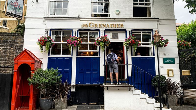 Spot chandeliers and elaborate gold framed pictures at The Grenadier in Belgravia. Credit: Shutterstock. Image courtesy of Shutterstock. A photo of the exterior of The Grenadier in Belgravia, a standalone white Victorian building with stairs leading up to the front door and flower baskets handing outside