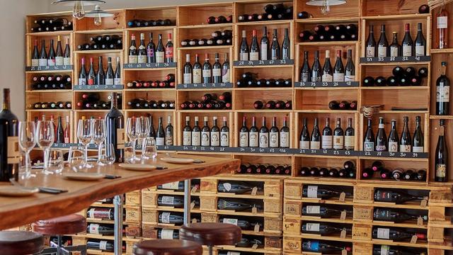 Discover your new favourite tipple at Antidote. Image courtesy of Antidote Wine Bar. Brown shells lines with many bottles of wine next to a table with wine glasses.