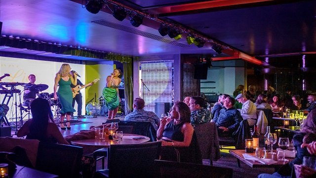 Live music at 100 Wardour Street. © 100 Wardour Street/Ayden Whitfield Indoor bar with two female singers and a live band on stage, with people sat on small tables watching the stage
