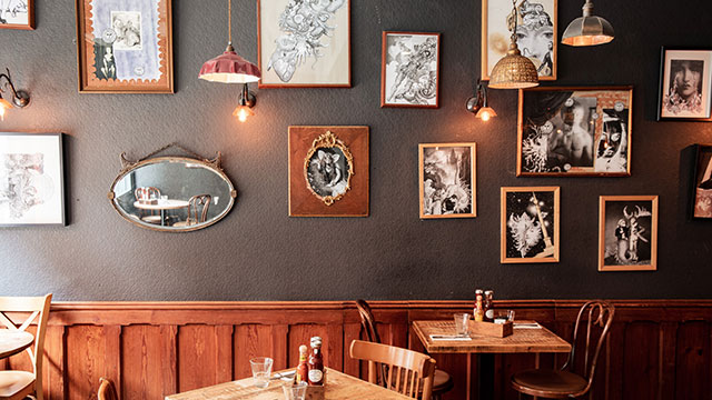 Balans Soho © Joe Howard. Image courtesy of Joe Howard / Balans Soho. The interior of Balans Soho with brown wooden tables and pictures on the wall.